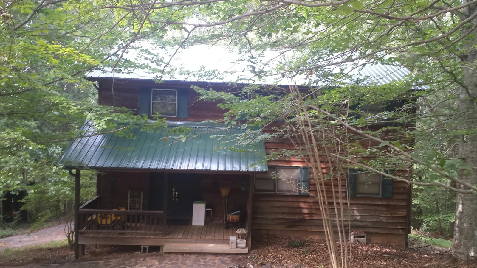 Green metal roof and covered porch on a log cabin in Byrdstown