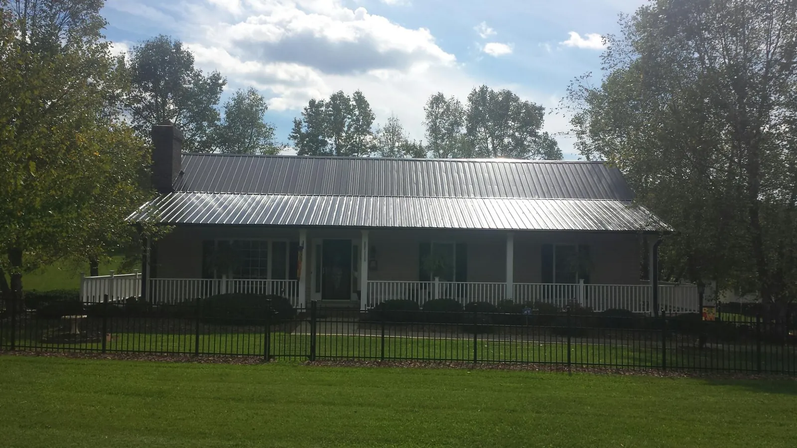 Gray metal roof on a brick ranch with a full width front porch — Gutter Guard Installation work by our crew in Byrdstown