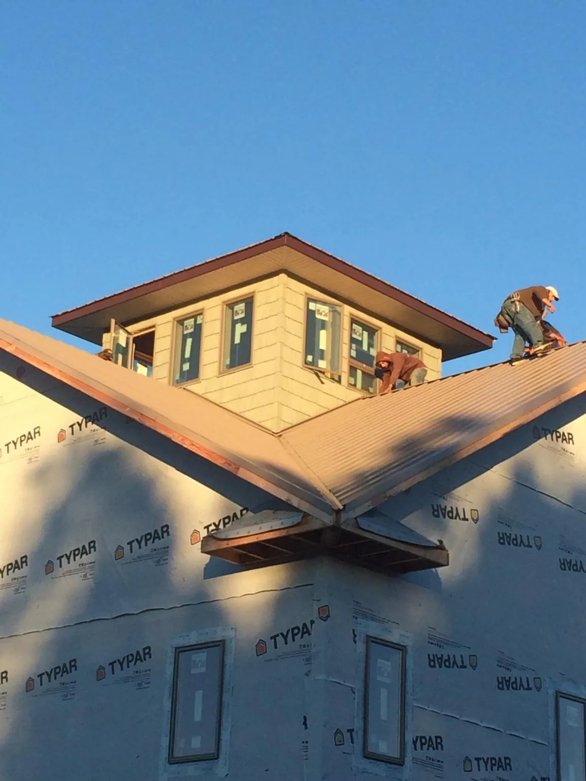 Roofers working around a rooftop cupola on a new metal roof at sunset — Roof Waterproofing in Byrdstown by Roofing Brothers